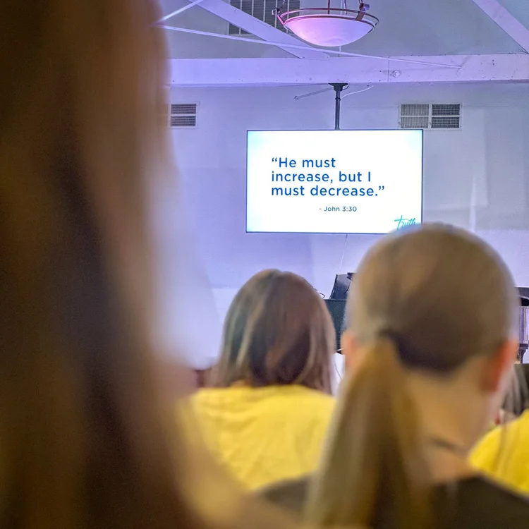 Campers listening during a teaching session with John 3:30 on the screen
